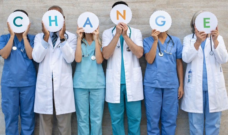 Heath care workers hold up signs that spell out “change”