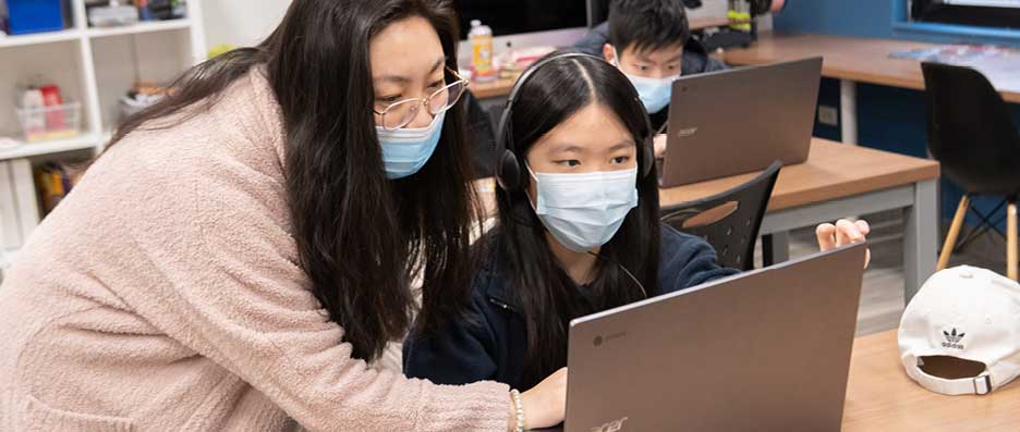 student and instructor looking at laptop