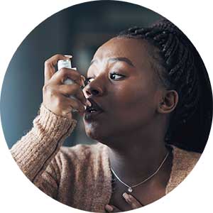 Woman experiencing an asthma exacerbation and using an inhaler