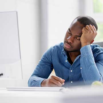 A man with closed eyes rests his head in his hand