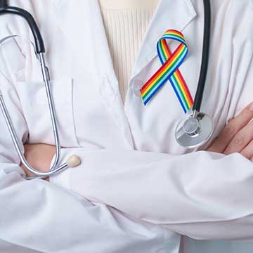A person wearing a white coat with a pride ribbon on it